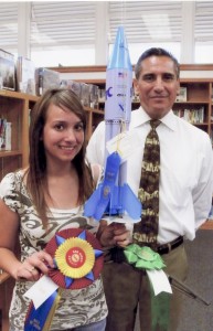 Ashley Garcia with her rocket design and winning ribbons with Mr. Montano.