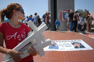 Jessica Rodriguez holds crosses during a rally in a busy Tijuana intersection to raise awareness of missing persons and in conjunction with Amnesty International's Day of the Disappeared. Rodriguez' husband has been missing for two years. Photo - David Maung