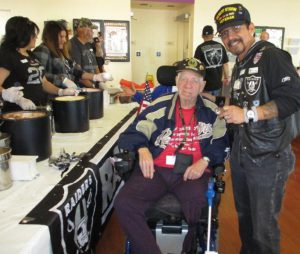 Moses Salas, right, a veteran and a member of the San Diego Chapter of the Raider Nation poses with a fellow veteran at the Chula Vista home where the fan club members saluted the veterans with an ice cream social.