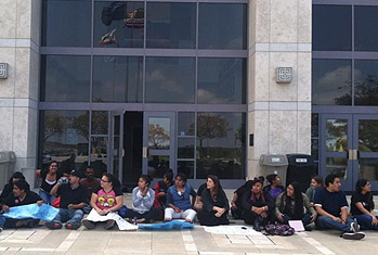Estudiantes sentados en el piso a las afuera de la oficina de la presidenta de la Universidad Karen Haynes.
