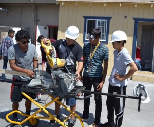 Students Lenin Orozco, Adam Aguilar, Pedro Negrete and Alex Madrid prepare a strip of moulding to be placed in their building project. 