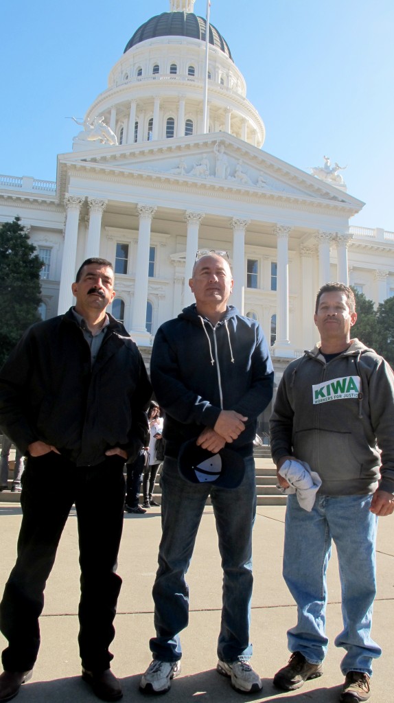 San Diego day laborers Andres Macias (left), Nelson Gamio, and Jorge Gracian pose in front of the state capitol building during their visit to the state assembly. (photo by Mark Day)