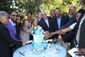 Rudolph Johnson, CEO of NHA (third from right) along with some of the board members, cut a cake to kick off their centennial celebration.