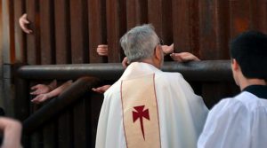 People on the Mexican side of the border reach through the fence into Nogales, Arizona, to receive Holy Communion from the Bishop of Tucson, Gerald Kicanas.
