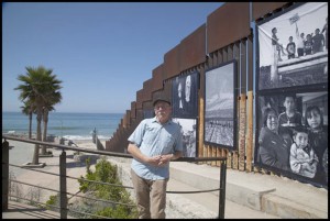 Photojournalist, David Bacon, stands infront of the exhibit featuring his photos of migrant farmworkers at the San Ysidro/Tijuana border.