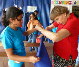 Annel snips fabric with a girl in Caluco in preparation for a Mass event that will highlight HIV/AIDS suffering in El Salvador, where six persons are infected each day. (Mary Jo McConahay)