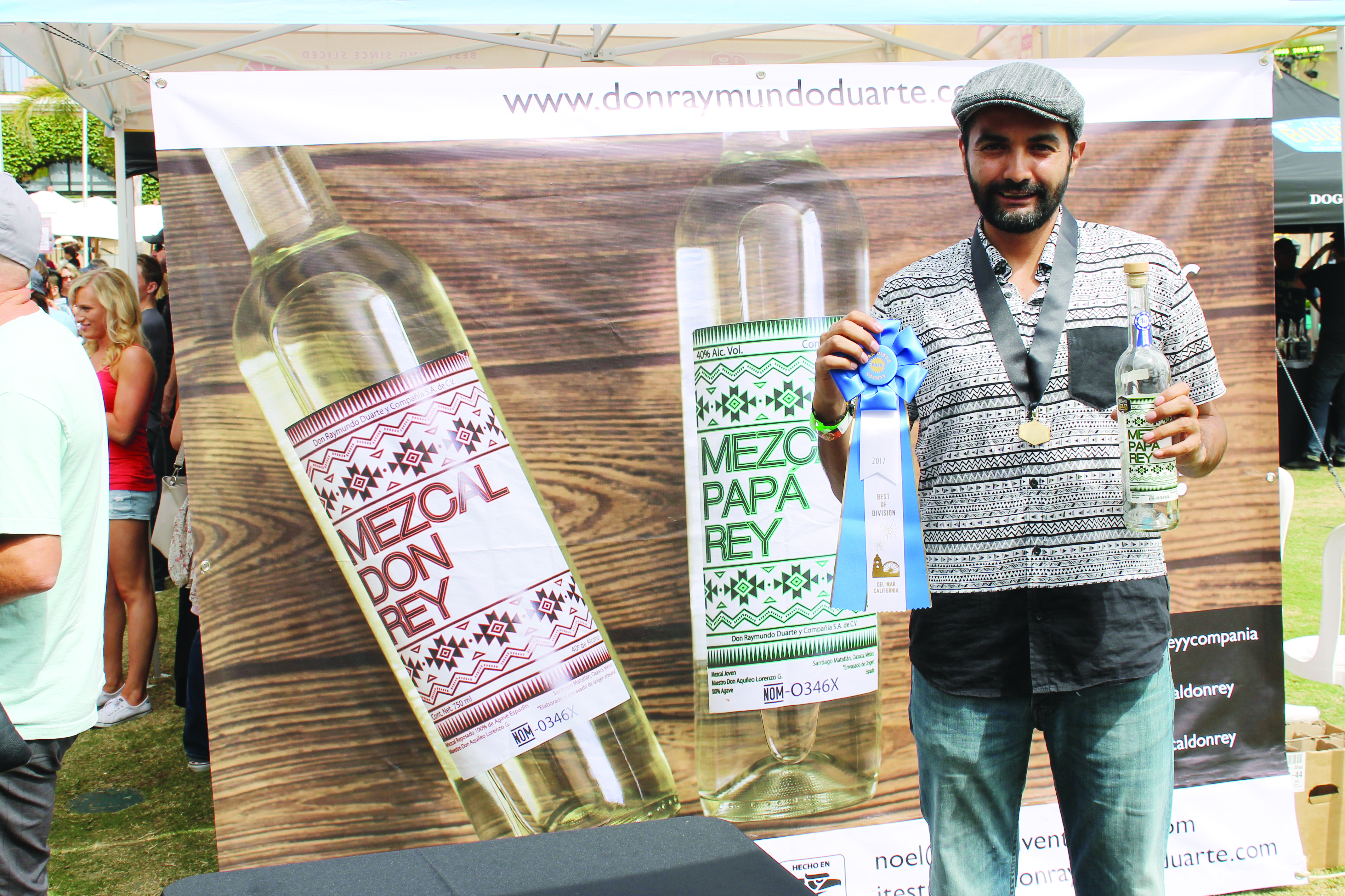 José Estrada Duarte holding his award winning mezcal and his first place ribbon. 